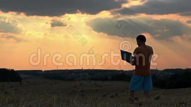 日落时分，<strong>一个人</strong>带着笔记本电脑在田野里，<strong>一个人</strong>在日落时分在上面工作